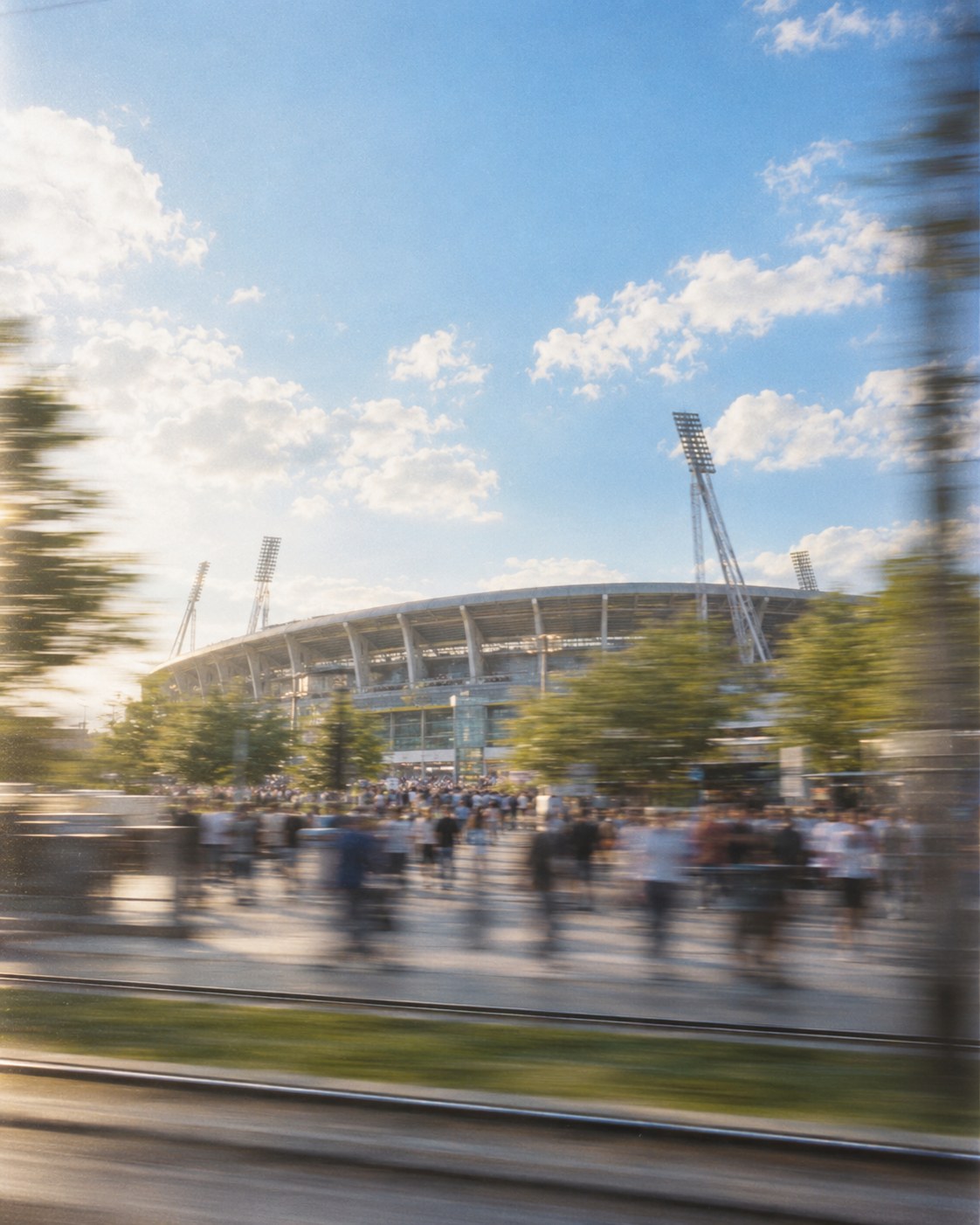 Fans walking to a football stadium on a sunny match day, seen from a moving tram